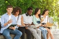 Group of cheerful students preparing for exam in park near university Royalty Free Stock Photo