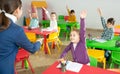 Cheerful pupils raising hands to answer