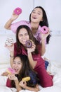 Group of cheerful teenage girls hold donuts on bed