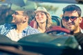 Group of cheerful young friends driving car and smiling in summer Royalty Free Stock Photo
