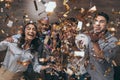 Group of cheerful young people standing together and celebrating with confetti Royalty Free Stock Photo
