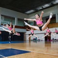 Group of cheerleaders jumping in the air demonstrate perfect stretching, active pretty girls in action, horizontal twine, hands