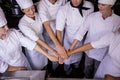 Group of chefs formig hands stack in kitchen