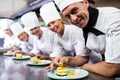 Group of chefs garnishing delicious desserts in a plate