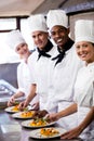 Group of chefs holding plate of prepared pasta in kitchen Royalty Free Stock Photo