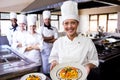 Group of chefs holding plate of prepared pasta in kitchen Royalty Free Stock Photo