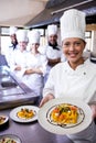 Group of chefs holding plate of prepared pasta in kitchen Royalty Free Stock Photo