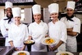 Group of chefs holding plate of prepared pasta in kitchen Royalty Free Stock Photo