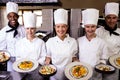 Group of chefs holding plate of prepared pasta in kitchen Royalty Free Stock Photo