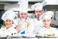 A group of chefs posing with delicious meal in high luxury restaurant.