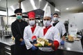 Group chefs standing together in the kitchen at restaurant wearing protective medical mask and gloves in coronavirus new normal