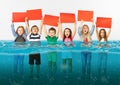Group of children with blank red banners standing in water of melting glacier, global warming
