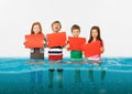 Group of children with blank red banners standing in water of melting glacier, global warming