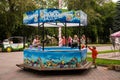 A group of children catch toy fish with fishing rods in a pool of water in an alley in central park on a summer day