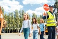 Group of children going out the school bus crossing road while driver holding stop sign attentive