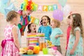 Group of children with clown blowing candles on cake at birthday party