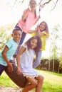 Group Of Children Having Fun With Friends Playing On Tire Swing In Garden Royalty Free Stock Photo