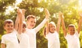 Group of children holding hands up in park on day. Volunteering with kids Royalty Free Stock Photo