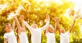 Group of children holding hands up in park on sunny day Royalty Free Stock Photo