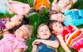 A group of children lying on the green grass in the Park. The interaction of the children. Royalty Free Stock Photo