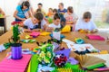 A group of children making crafts out of colored paper. Lifestyle scene of children making hand made goods together and having