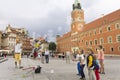 A group of children play with soap bubbles in middle of old town market with Royal Warsaw Castle