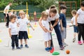 Group of children playing hockey within polygon. Sport school. Coach helping