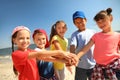 Group of children putting hands together at sea beach on sunny day. Summer camp Royalty Free Stock Photo