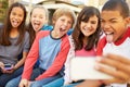 Group Of Children Sitting On Bench In Mall Taking Selfie Royalty Free Stock Photo