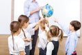 Group of children and teacher holding a globe