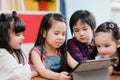 Group of children using tablet in classroom, Multi-ethnic young boys and girls happy using technology for study and play games at Royalty Free Stock Photo