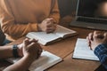 A group of Christians sit together and pray around a wooden table with blurred open Bible pages in their homeroom. Prayer for Royalty Free Stock Photo