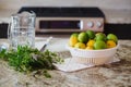 Group of citrus fruits yellow green lemons, limes, peppermint in dish on table ready for juice preparation, jar on background