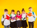 Group of classmates reading book over yellow background.