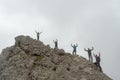 Group of climbers standing on a jagged mountain peak and waving their hands in the air