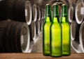 Group of cold wet beer bottles in the cellar with vintage kegs Royalty Free Stock Photo