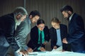 Group of colleagues meeting in briefing room for project discussion. Professionals looking on analytical report for