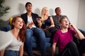 Group Of College Friends Celebrating Whilst Watching Sports Game On TV In Shared House Royalty Free Stock Photo