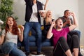 Group Of College Friends Celebrating Whilst Watching Sports Game On TV In Shared House Royalty Free Stock Photo