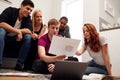 Group Of College Students In Lounge Of Shared House Studying Together