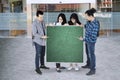 Group of college students pointing on green board with copy space Royalty Free Stock Photo