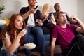 Group Of College Students In Shared House Watching TV And Eating Popcorn Royalty Free Stock Photo