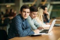 Group of college students studying in the school library, a girl and a boy are using a laptop and connecting to internet Royalty Free Stock Photo