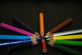 Group of color pencil crayons roundly arranged and pointing into center on background