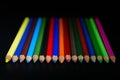 GROUP OF COLORED PENCILS ALIGNED ON BLACK BLACKGROUND Royalty Free Stock Photo