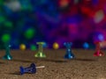 A group of colorful thumbtacks are on a cork surface against a very colorful background Royalty Free Stock Photo
