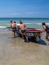 Group of competing surf-lifesavers push surf-boat into sea Royalty Free Stock Photo