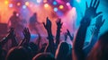 A group of concertgoers sway to the music back facing the camera their hands reaching towards the stage. The colorful Royalty Free Stock Photo