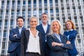 Group of confident business professionals posing in front of a modern building