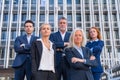 Group of confident business professionals posing in front of a modern building